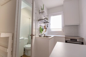 A compact kitchen with white cabinetry, a built-in oven, and a window providing natural light. - Coqueto Apartamento a 5 Minutos del Retiro (Madrid)