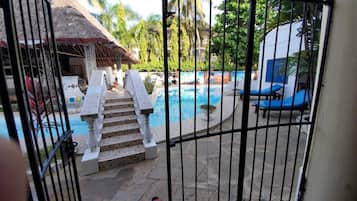 Step into a tranquil oasis with a pool surrounded by lush palm trees and tropical vegetation.