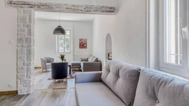A modern living room with a grey sofa, a black chair, and a hanging light fixture. - Ardeche in Provence with shady park (Pont-Saint-Esprit)