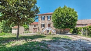 A stone building with a red-tiled roof, a central staircase, and a surrounding garden. - Ardeche in Provence with shady park (Pont-Saint-Esprit)
