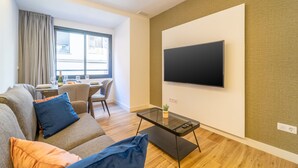 A modern living room with a sofa, a coffee table, and a TV mounted on the wall. - Estudio Prime (Alicante (Alacant))