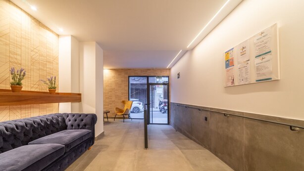 A modern hallway with a sofa, a chair, and a wall-mounted information board. - Estudio Prime (Alicante (Alacant))