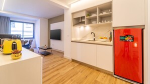 A modern kitchen with white cabinets, a red refrigerator, and a dining area with a yellow toaster. - Estudio Prime (Alicante (Alacant))