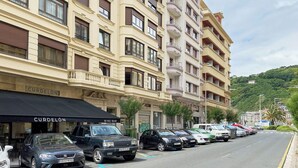 Ein mehrgeschossiges Hotel mit Balkonen, einer Weinbar und geparkten Autos entlang der Straße.