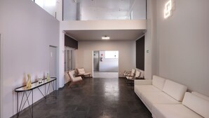 A spacious, modern interior with a white sofa, a small table, and two chairs. - Hotel Royal Park Piracicaba (Piracicaba)