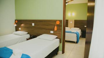 A hotel room with two single beds, a wooden headboard, a mirror, and a bathroom visible through an open door.
