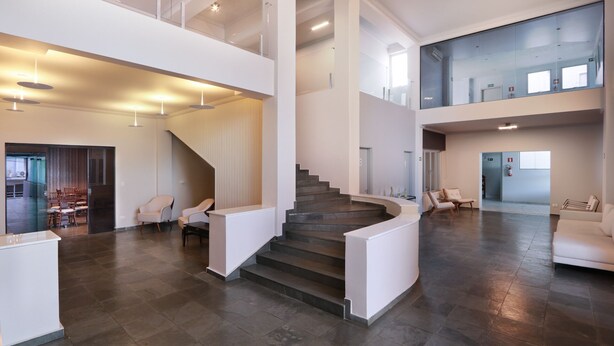 A spacious interior with a central staircase, multiple seating areas, and a high ceiling. - Hotel Royal Park Piracicaba (Piracicaba)
