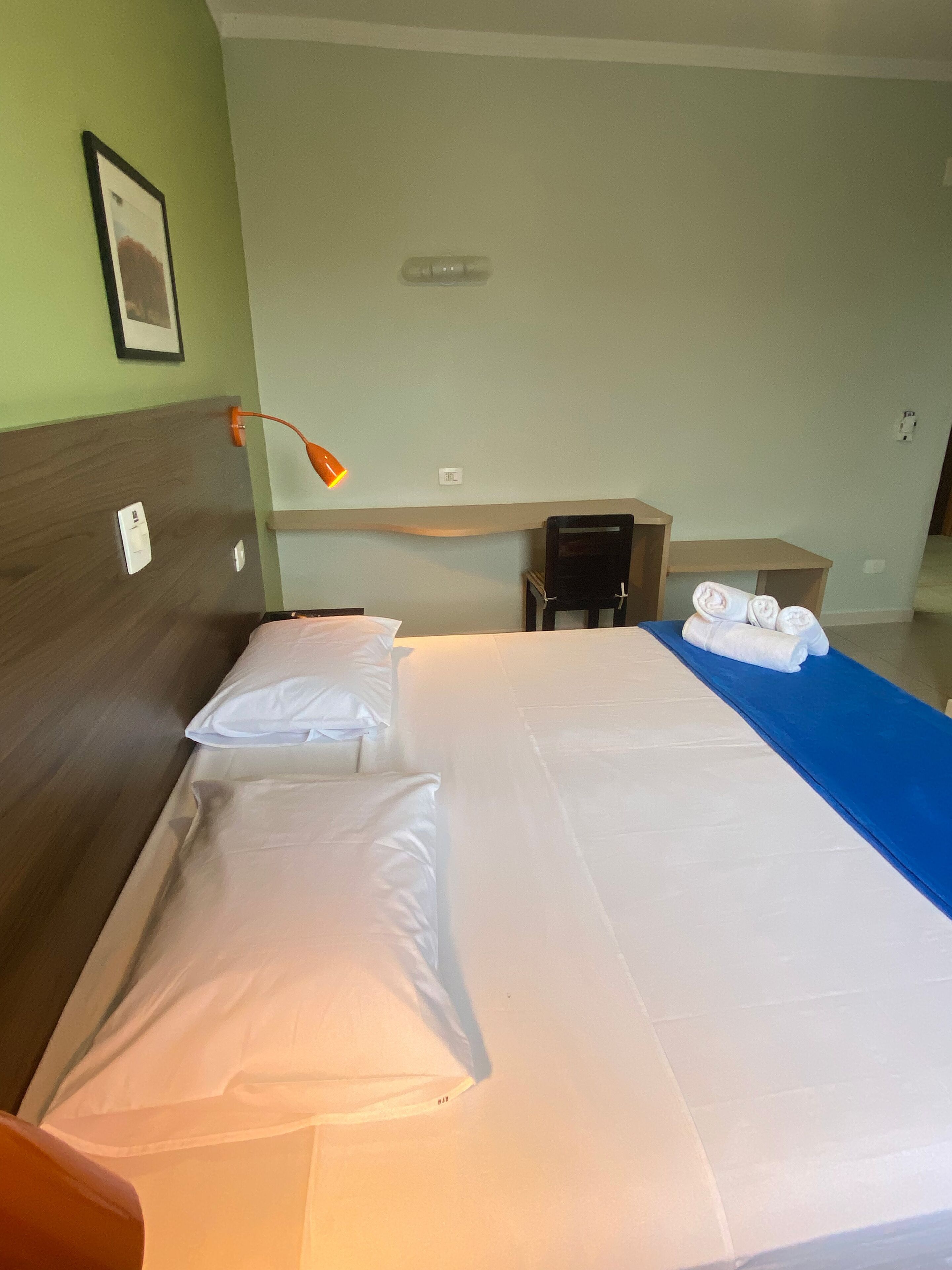 A hotel room with a bed, a desk, and a chair.