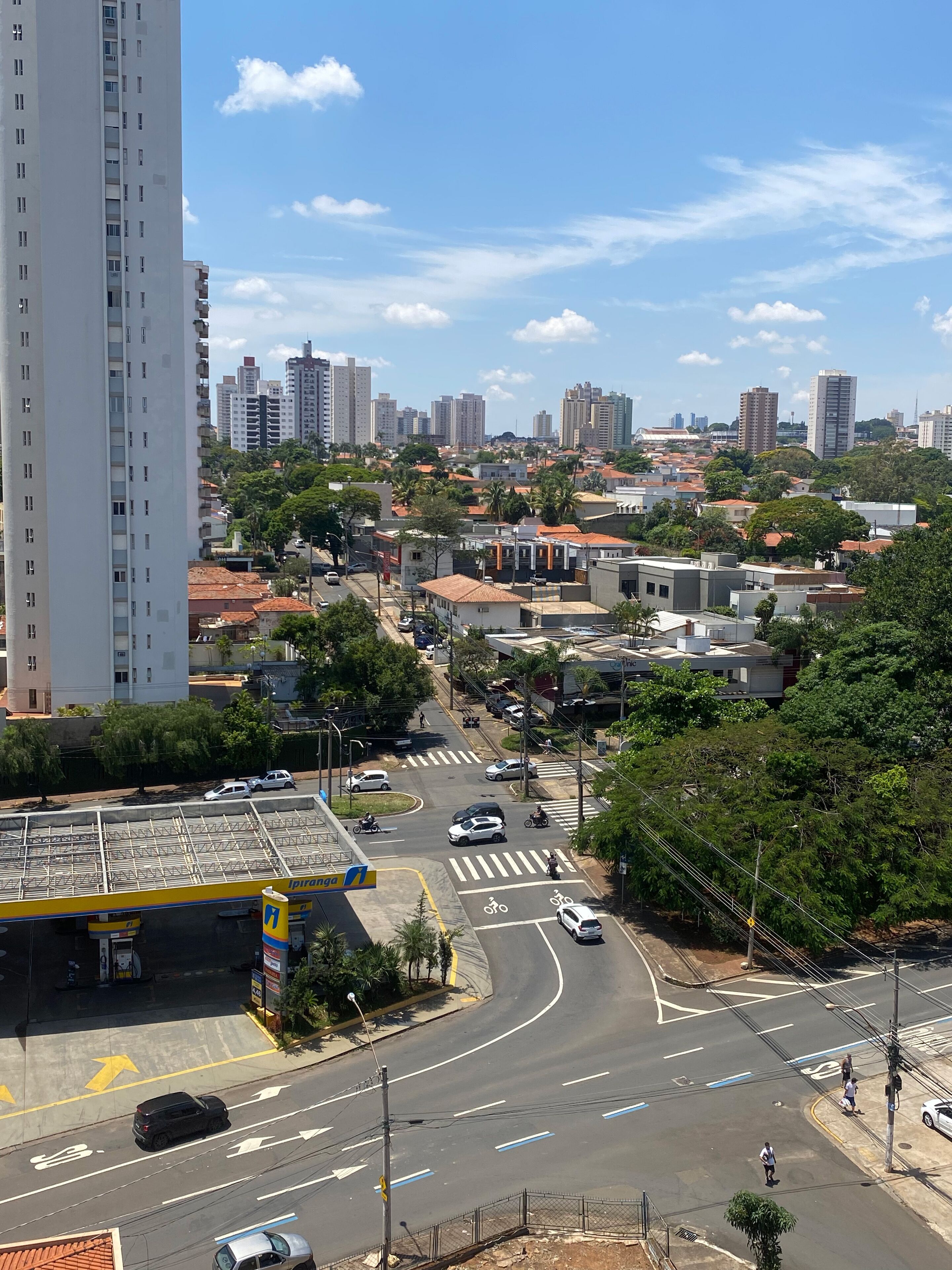Un paisaje urbano con rascacielos, una gasolinera y un paso de peatones.