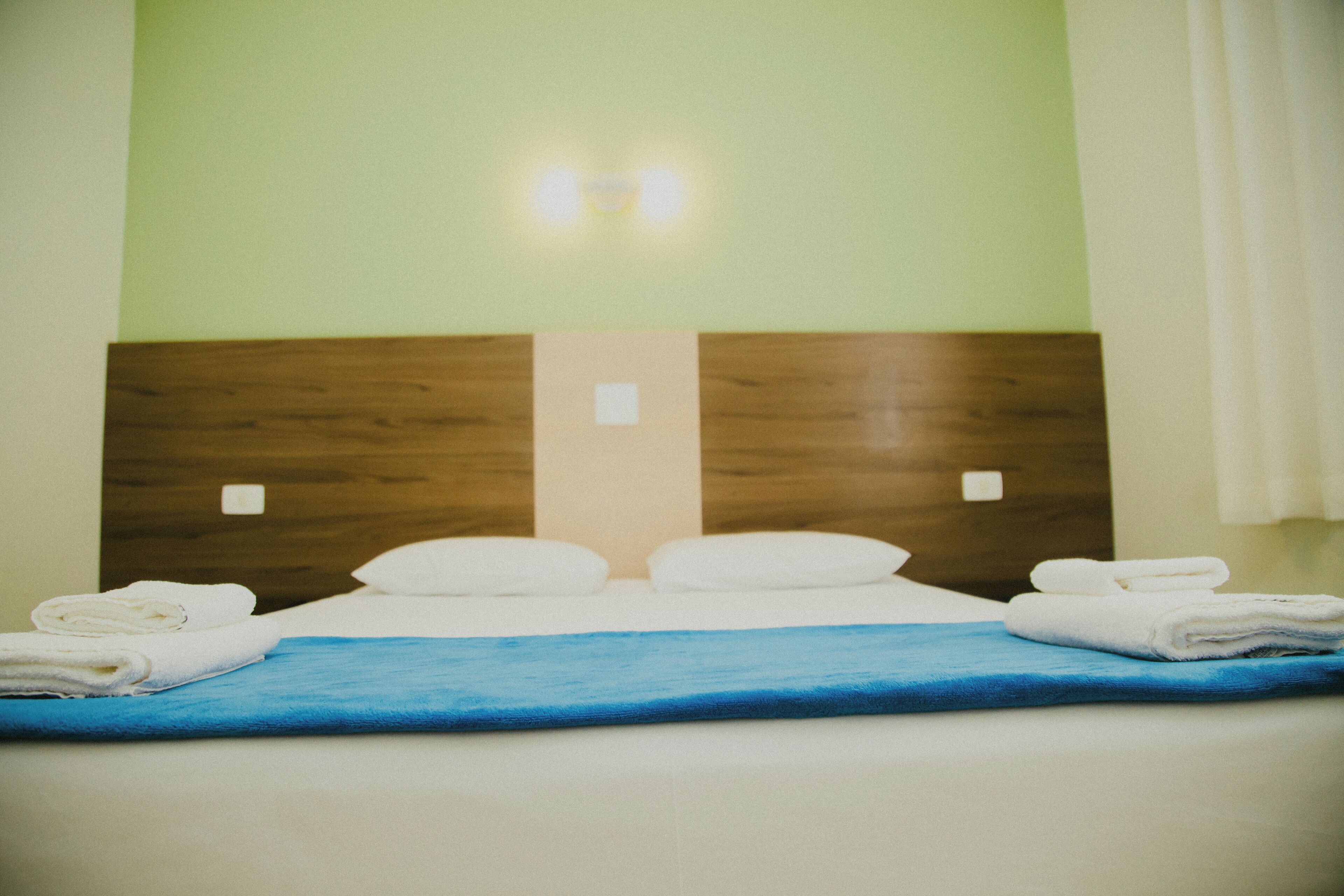 Een hotelkamer met een houten hoofdbord, witte kussens en een blauw sprei.
