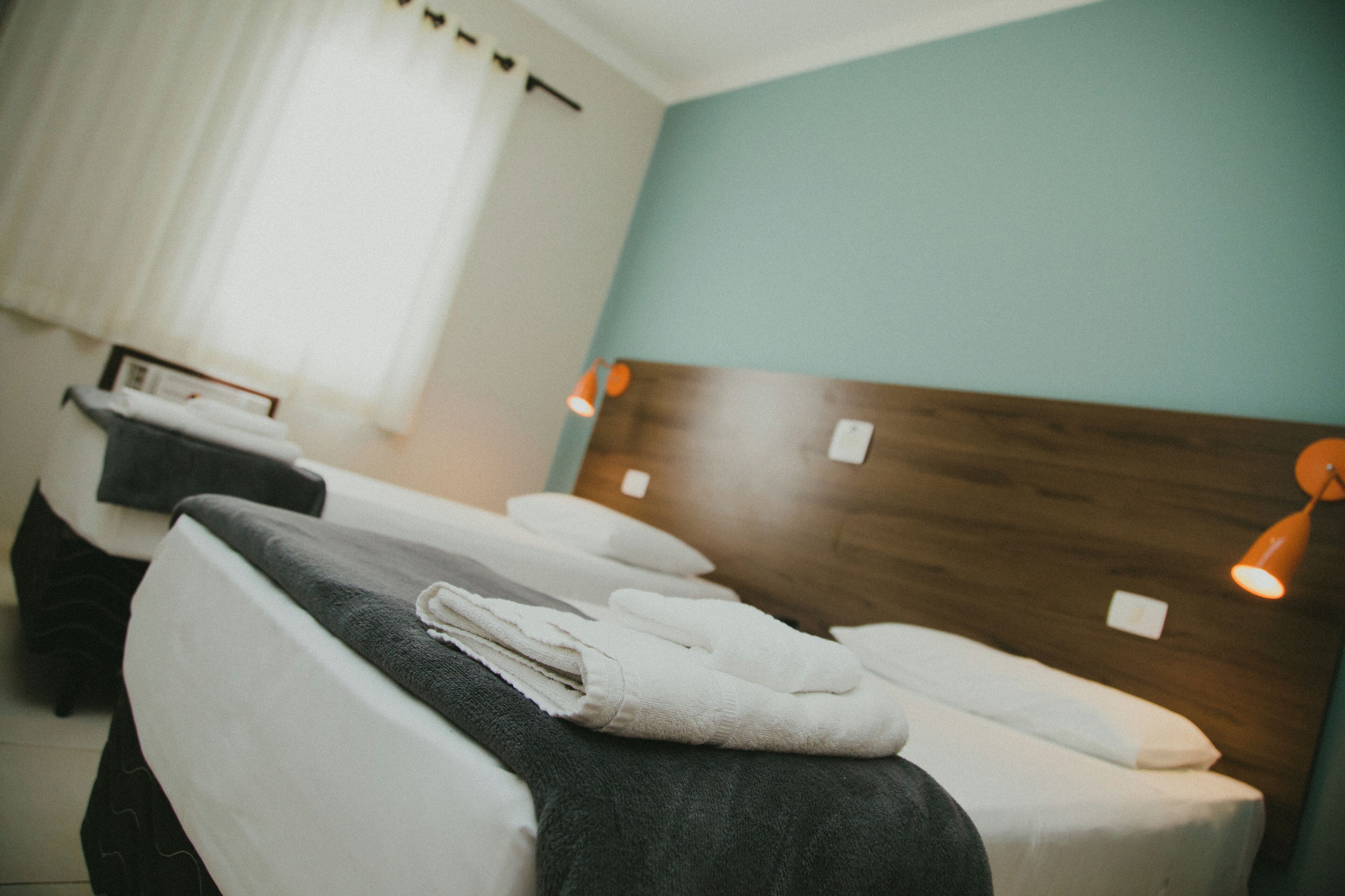 A hotel room with two beds, each with a wooden headboard and white linens.