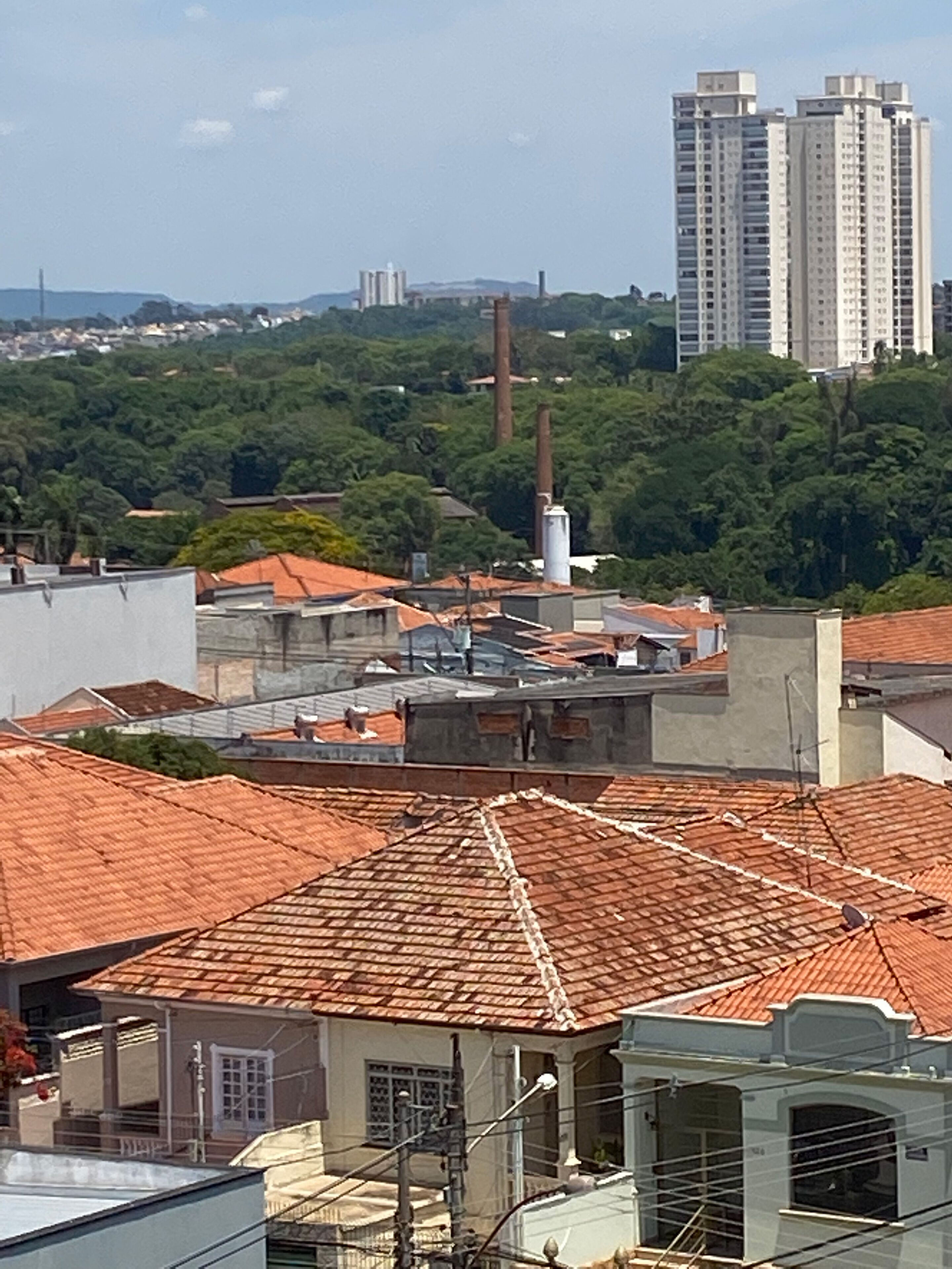 A rooftop view of buildings with red-tiled roofs, some with visible antennas and satellite dishes.