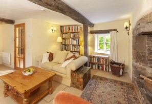 A cozy living room with a sofa, a wooden coffee table, a bookshelf, and a fireplace.
