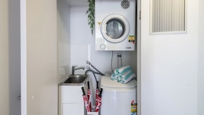 Un área de lavandería compacta con lavadora, un lavabo y un perchero.