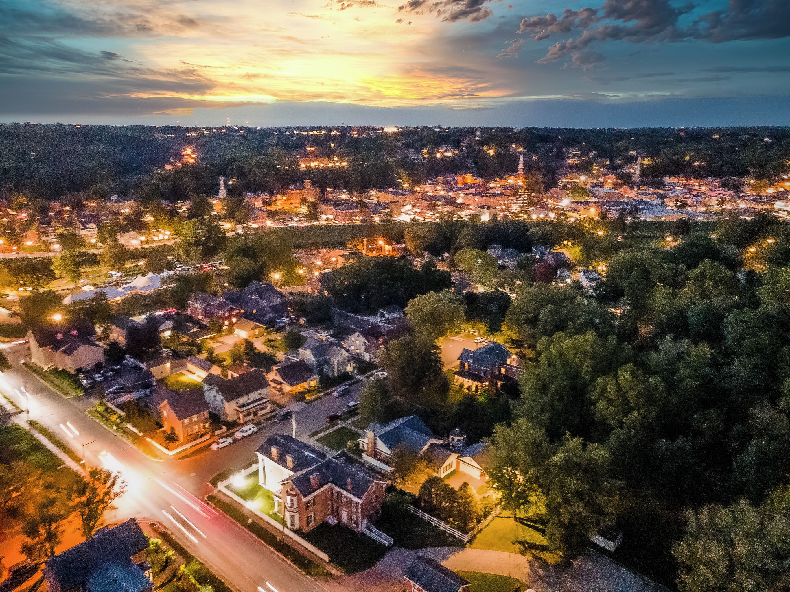 An aerial view of a town at dusk with illuminated streets and buildings.