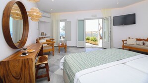 A hotel room with a bed, wooden desk, chairs, a television, and a balcony with a view. - Christiana Hotel (Paros)
