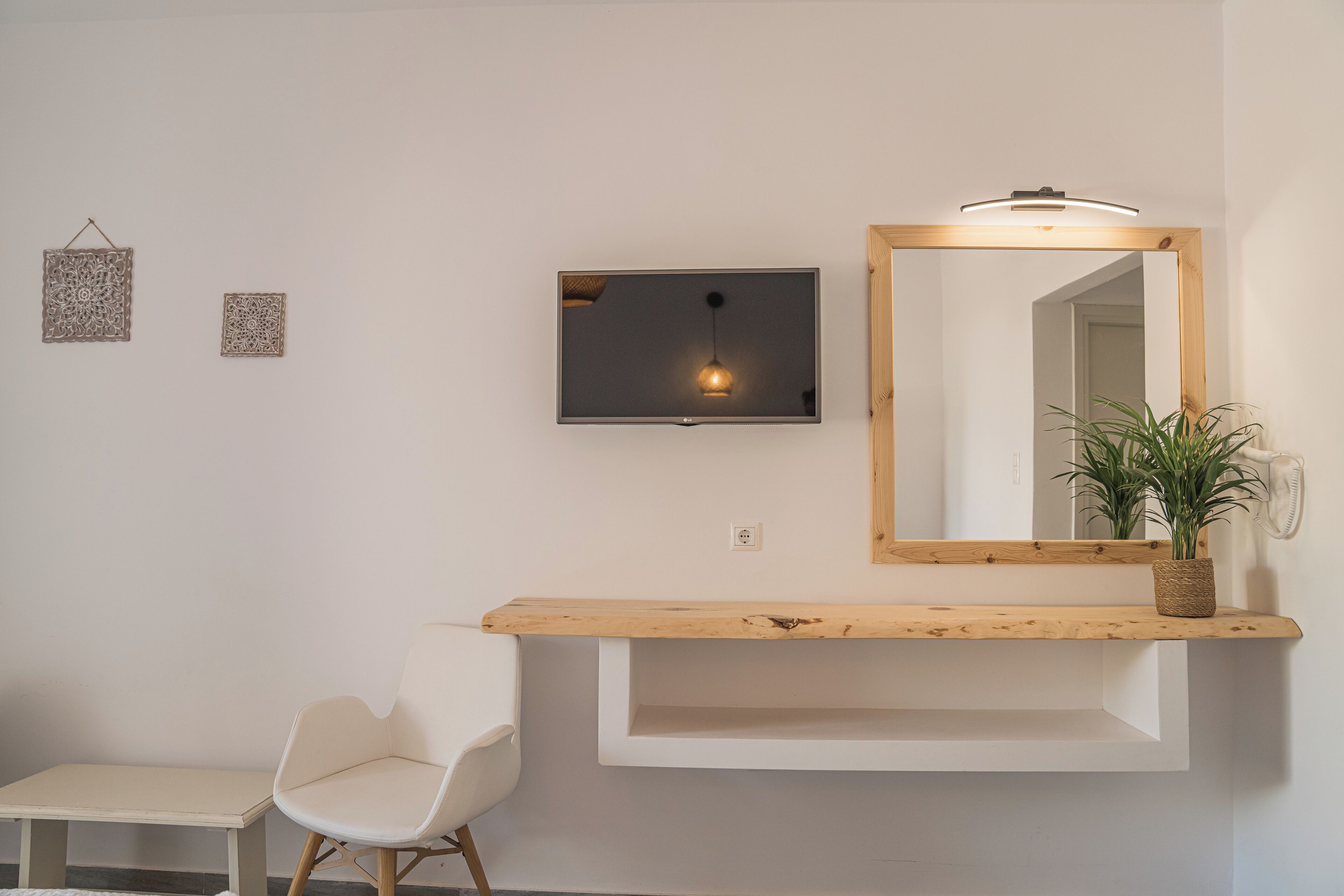 A modern bathroom with a wooden vanity, a white chair, a mirror, and two wall-mounted light fixtures.