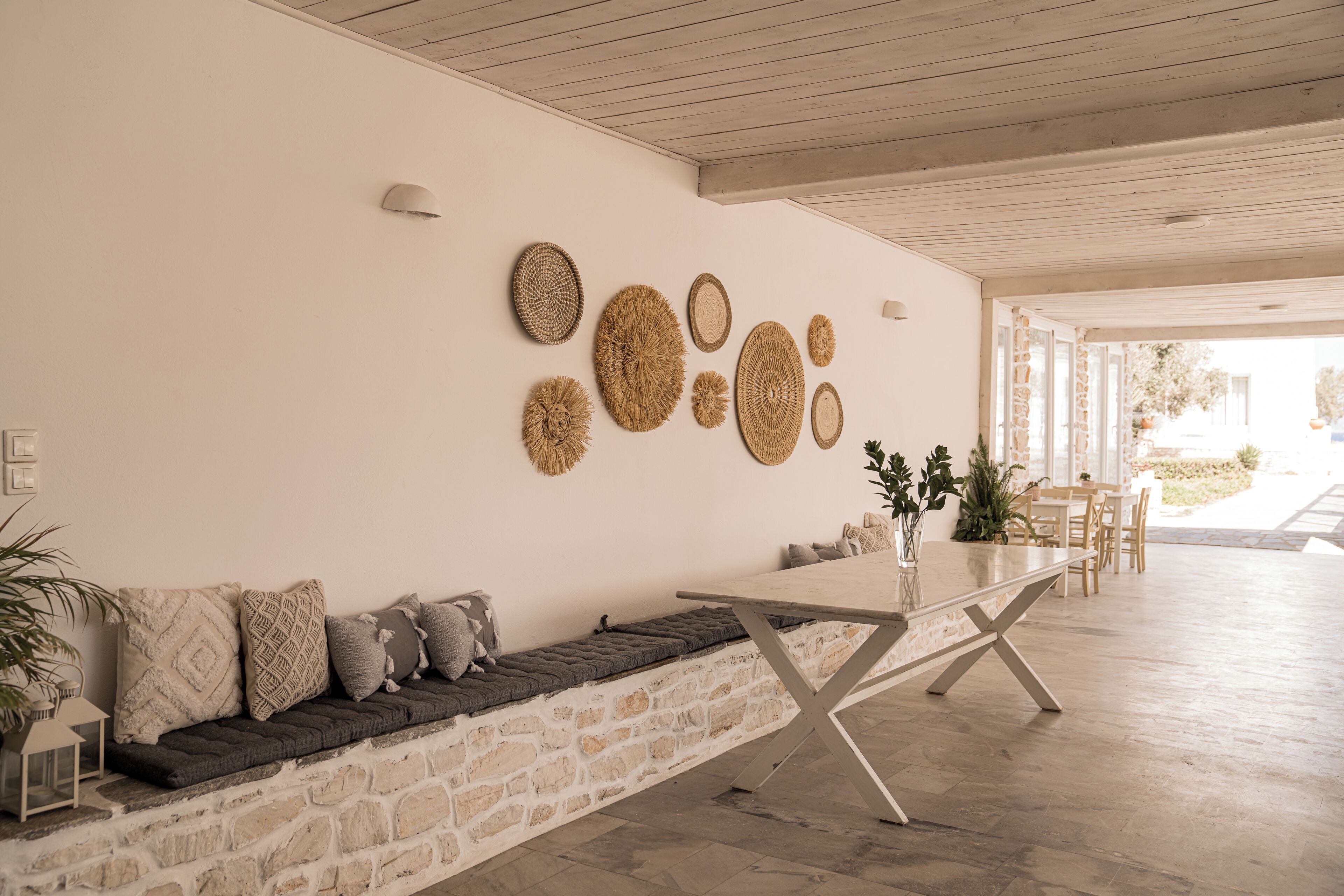 A modern interior with a stone bench, a dining table, and wall-mounted woven art pieces.
