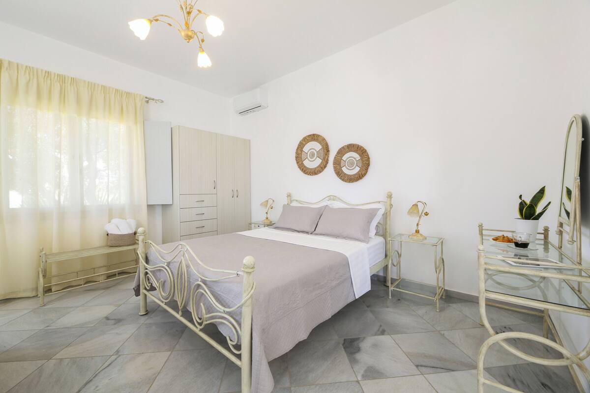 A bedroom with a bed, bedside tables, a mirror, and decorative wall art.