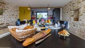 A dining area with a table set for breakfast, including bread, pastries, and a bottle of wine. - La Lisière du Morvan (Magny-Lormes)