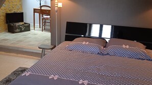 A bedroom with a bed, a lamp, a chair, a small table, and a wall with a heart decoration. - La Lisière du Morvan (Magny-Lormes)