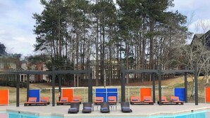 Une piscine avec des chaises longues et un espace salon abrité.