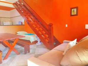 Cozy retreat with a small bed, wooden table, and beige sofa, perfect for a relaxing stay.