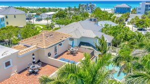 A residential area with a swimming pool, a patio with outdoor furniture, and a view of the ocean. - Gertrude's Siesta | 6 Terraces, Rooftop, Pool, 1-min to Beach and Village! (Siesta Key)