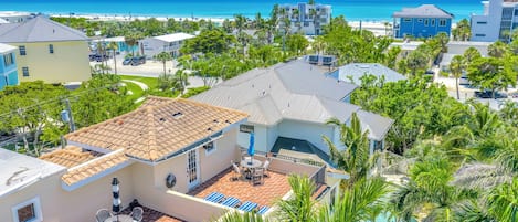 A residential area with a swimming pool, a patio with outdoor furniture, and a view of the ocean.