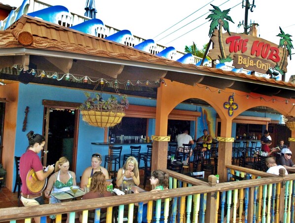 Enjoy a meal in the open-air dining area with wooden tables and chairs.