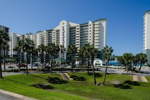 A hotel with multiple white buildings, palm trees, and a clear blue sky.