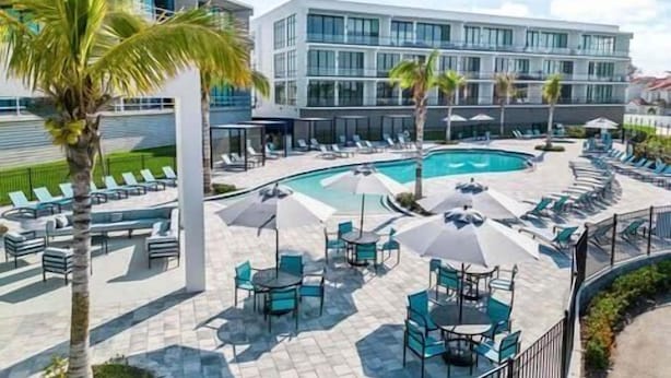 Et moderne hotel med swimmingpool, liggestole og udendørs siddepladser.
