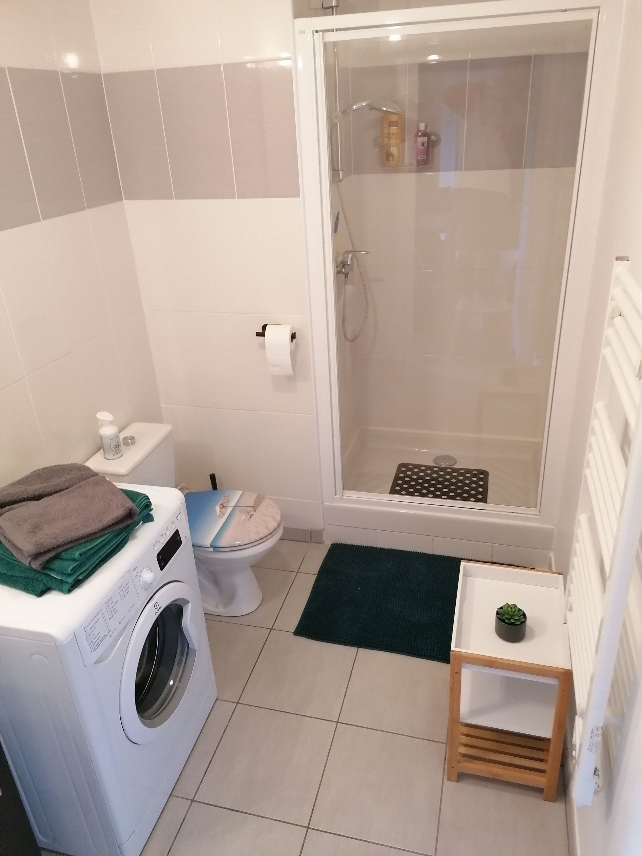 Ein kleines Badezimmer mit Waschmaschine, Toilette und Duschkabine.