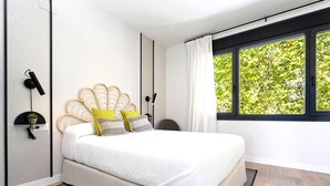 Un dormitorio moderno con una cama, una ventana con cortinas, una lámpara de pared y una planta pequeña.
