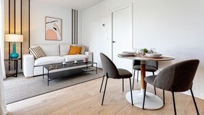 Una sala moderna con sofá, mesa de centro y comedor con sillas.