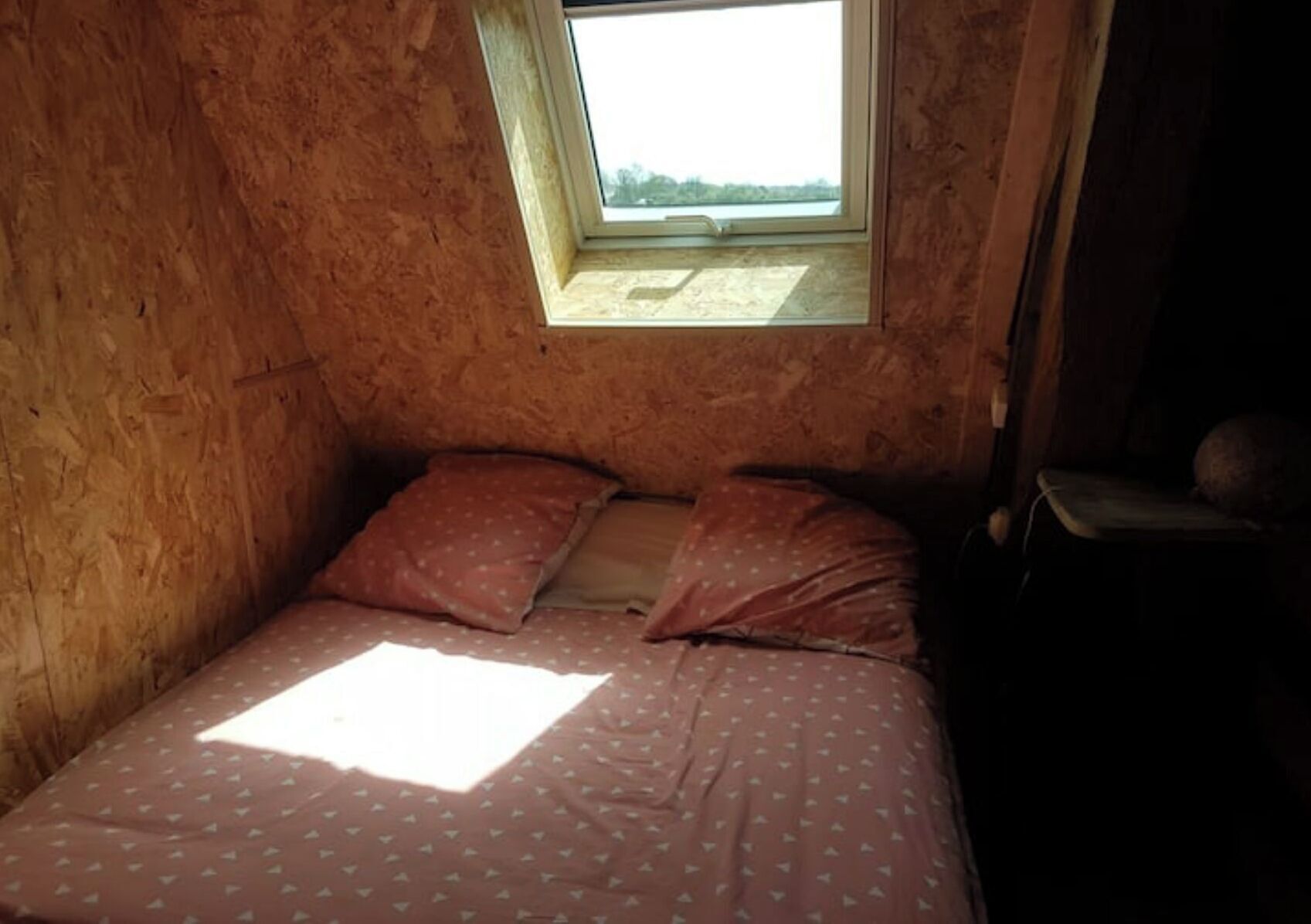 A small, single-bed room with a sloped ceiling and a skylight.