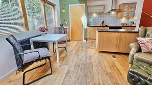 A modern kitchen with wooden cabinets, a built-in island, and a dining area with a table and chairs.
