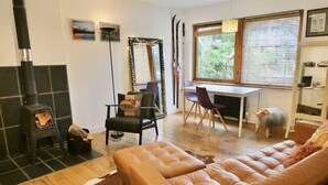 A cozy living room with a fireplace, a sofa, a dining table with chairs, and a dog.