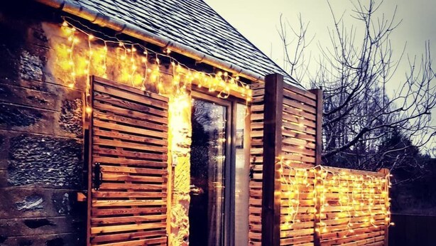 A rustic wooden cabin with a wooden deck and a glass door.