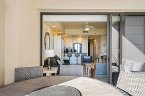 Quarto de hotel moderno com área de refeições, cozinha ao fundo e porta de correr que dá para uma varanda.