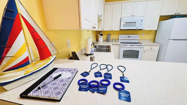A kitchen with white cabinets, a microwave, and a stove. There is a sailboat model and a notebook with a pen on the counter.
