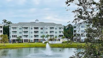 A multi-story hotel with a central courtyard, a fountain, and a lake.