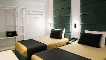 Une chambre d’hôtel avec deux lits, une armoire et une table de chevet avec un téléphone.