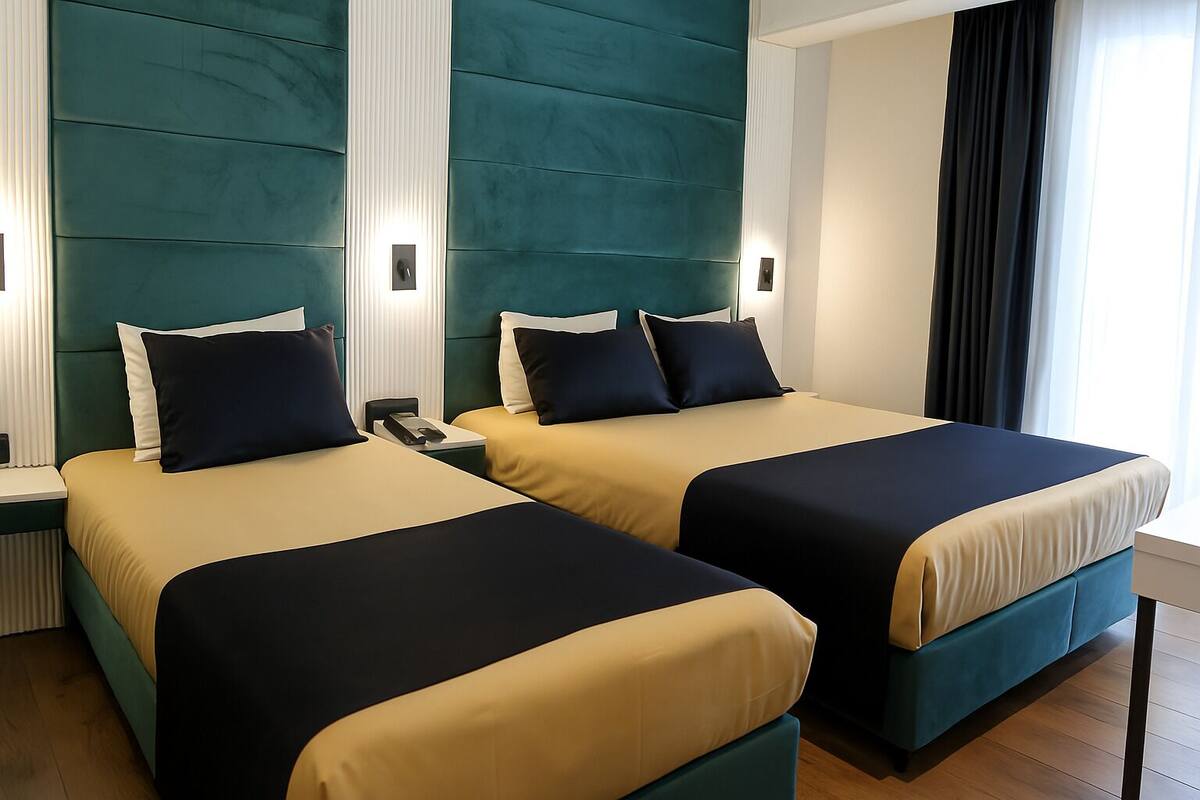 A hotel room with two beds, each with a headboard, bedside tables, and a telephone.