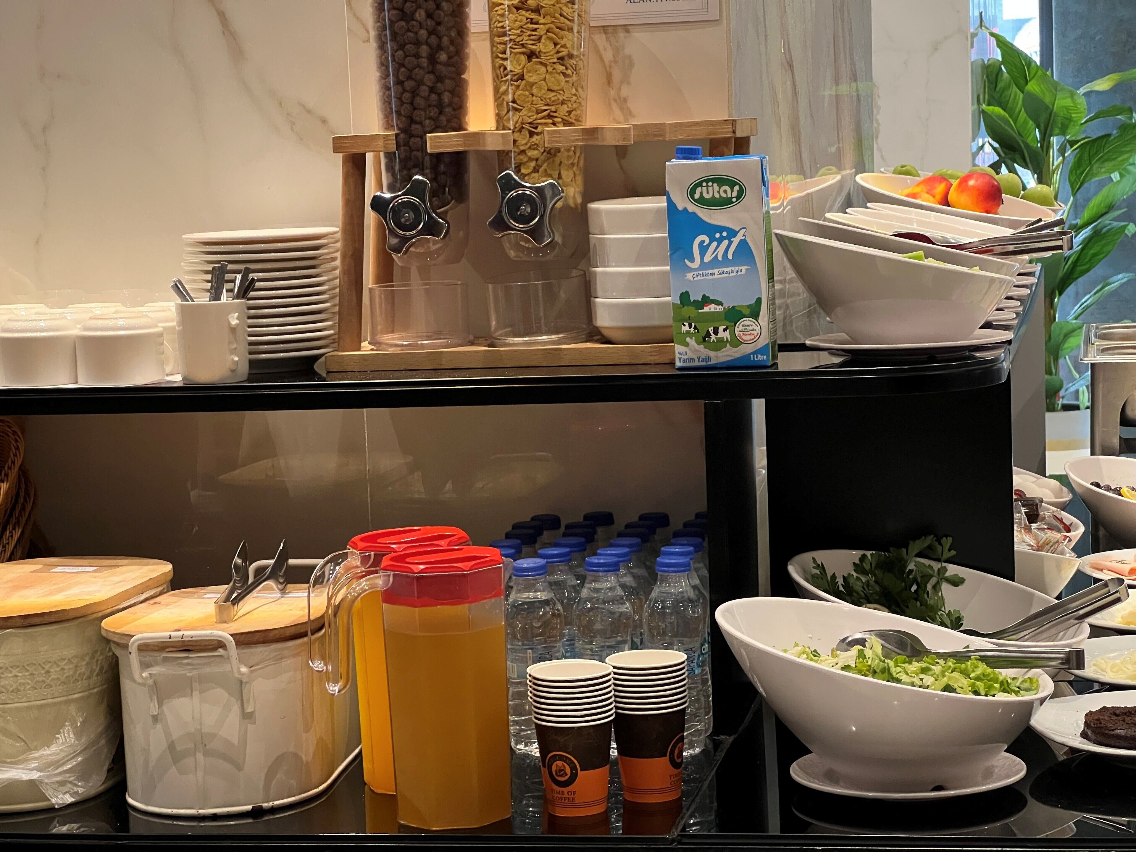 A buffet setup with various food items, a milk carton, and beverage dispensers.