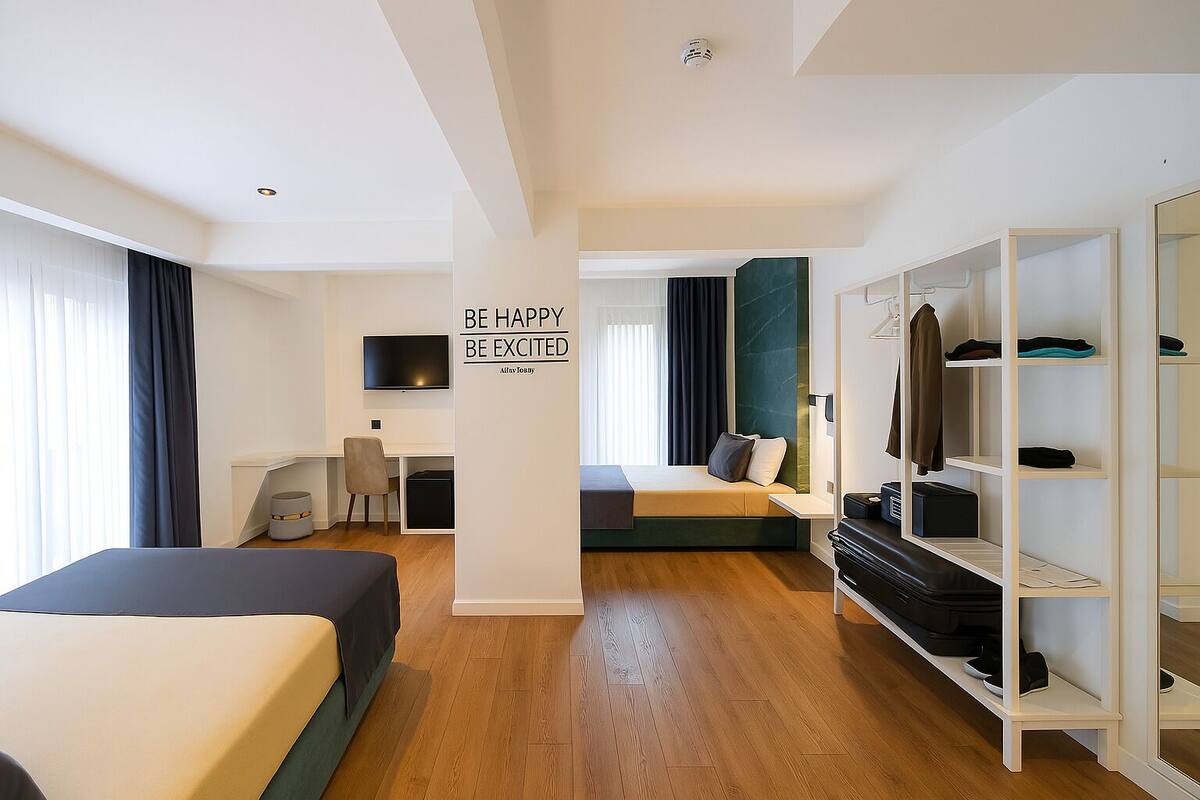 A modern hotel room with a bed, a desk, a TV, and a wardrobe.