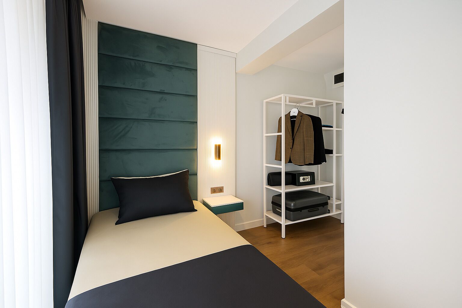 A modern bedroom with a bed, a bedside table, a nightstand, a wardrobe, and a wall-mounted light.