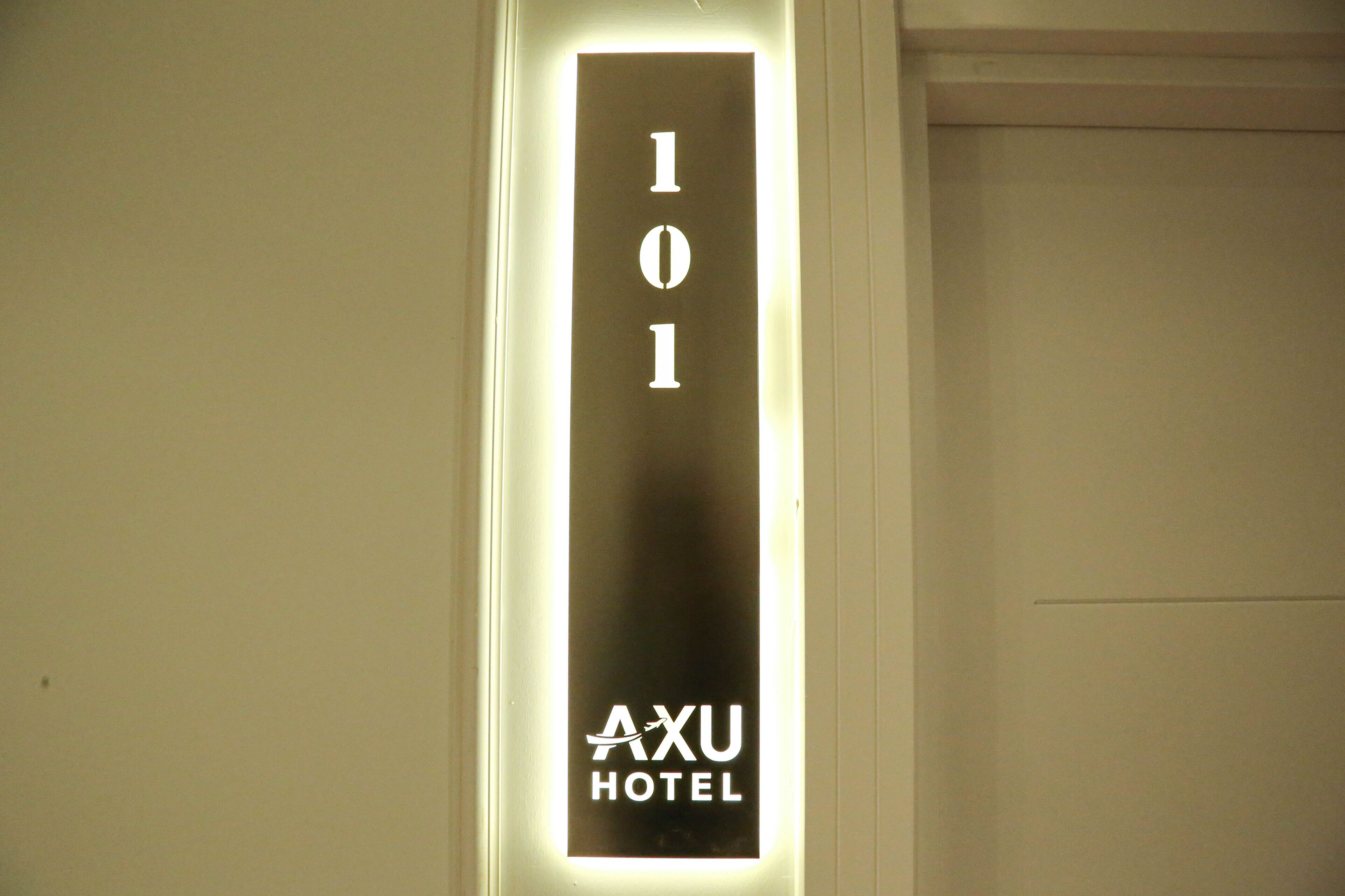 A hotel room door with a sign indicating room number 101 and the name 'AXU HOTEL'.