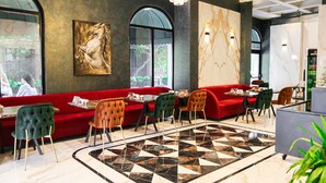 A restaurant with a red sofa, green and orange chairs, and a marble floor. - Axu Airport Hotel (Arnavutköy)