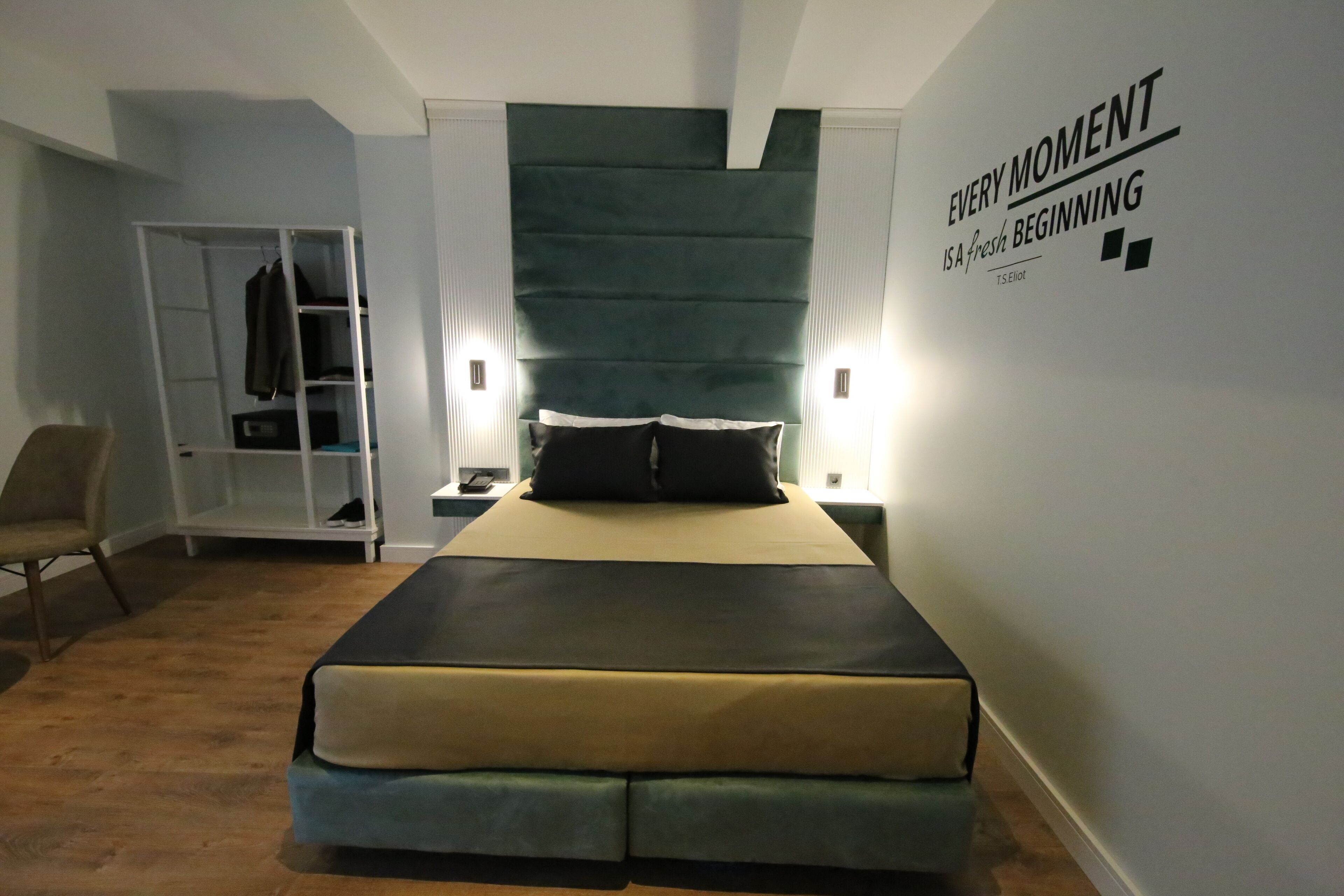 A modern bedroom with a bed, a wardrobe, and a wall with motivational text.